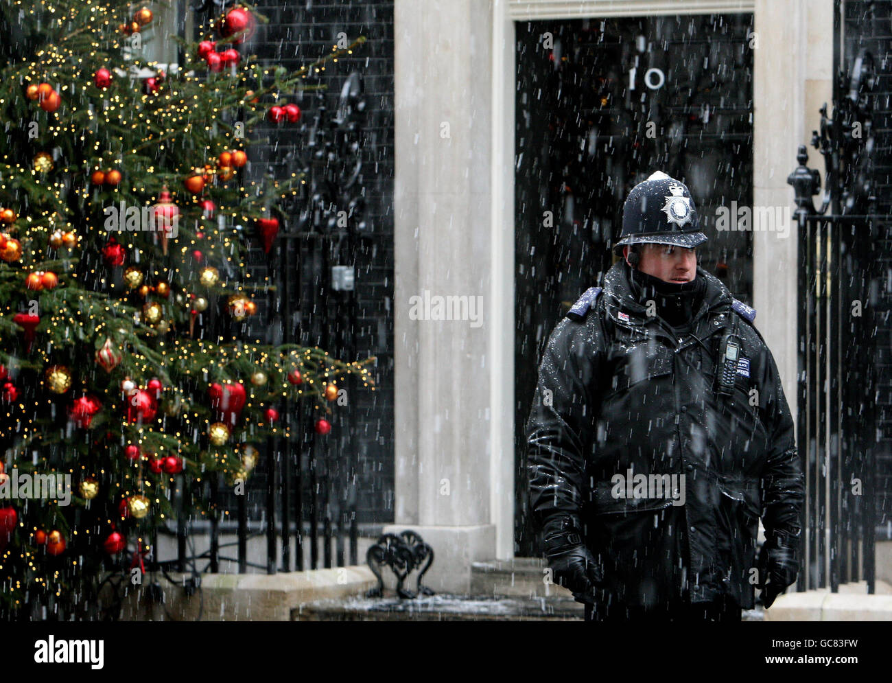 Ein Polizist steht vor der Downing Street 10, Westminster, als im Zentrum Londons Schnee fällt. Stockfoto
