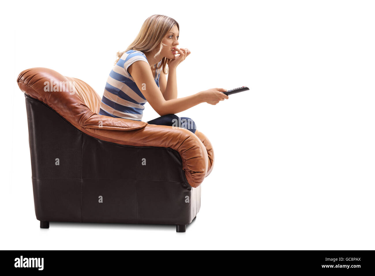 Junge Frau vor dem Fernseher und beißen Sie ihre Nägel sitzt auf einem Sessel isoliert auf weißem Hintergrund Stockfoto