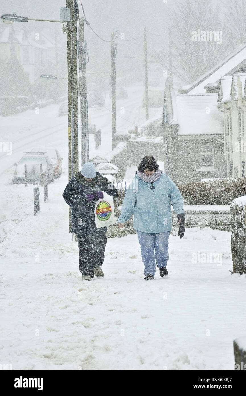 Die Menschen kommen durch einen Schneesturm zu den Geschäften, als im Südwesten Großbritanniens in der Nähe von Two Bridges, Dartmoor, Devon, ein frischer Schnee fällt. Stockfoto