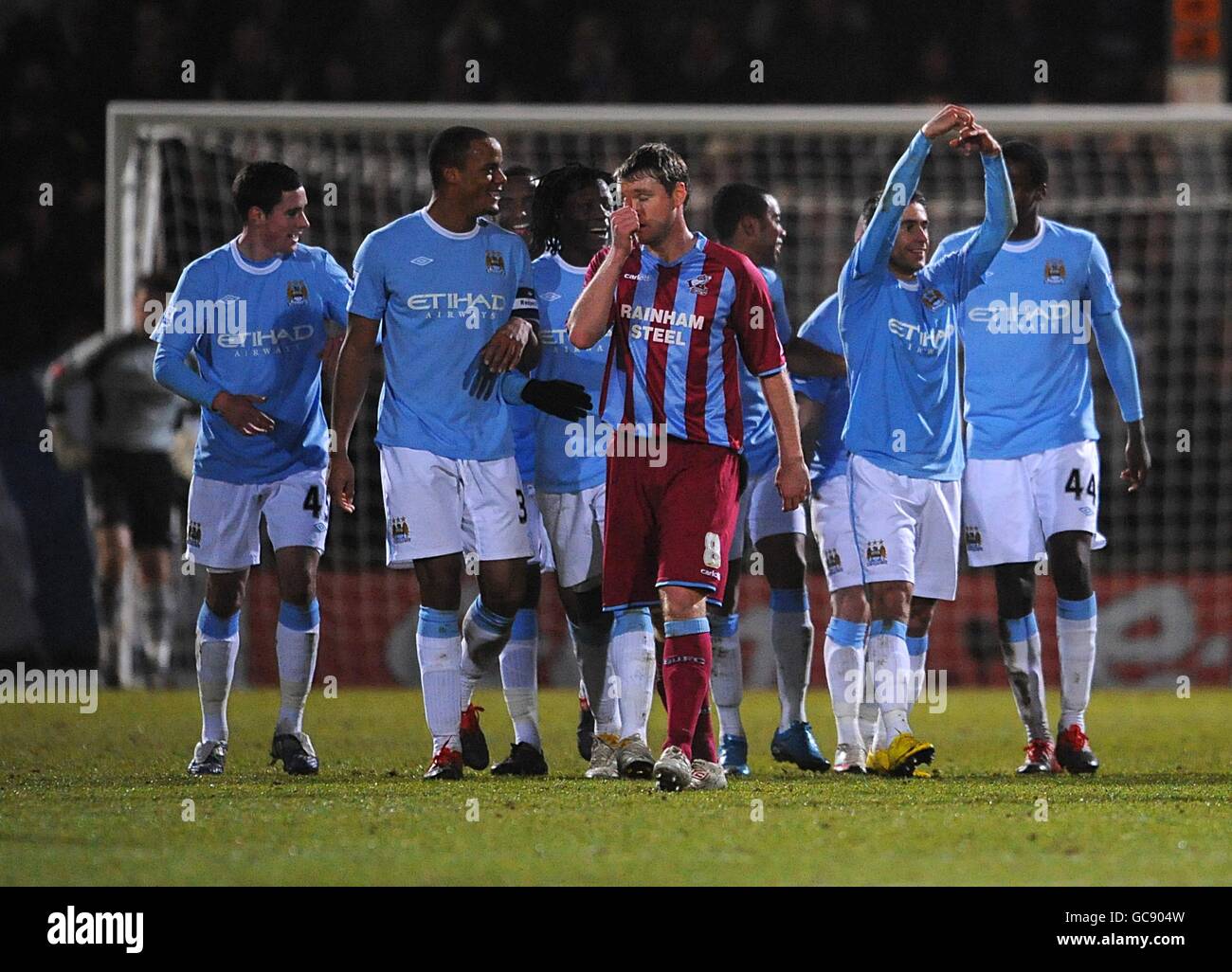 Grant McCann von Scunthorpe United (Mitte) steht depriziert, als Silvio Sylvinho von Manchester City (2. Rechts) mit seinen Teamkollegen feiert, nachdem sie das dritte Tor des Spiels erzielt hatten Stockfoto