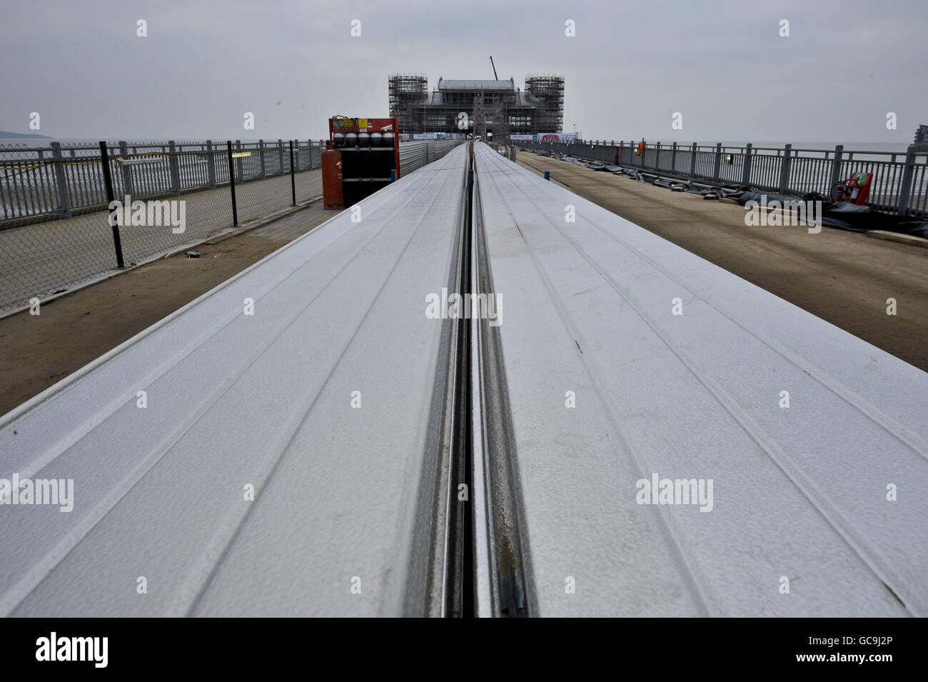 Die Bauarbeiten am Grand Pier in Weston-super-Mare werden fortgesetzt, um die Fertigstellung und die Wiedereröffnung im Sommer 2010 nach der Zerstörung durch einen Brand im Juli 2008 zu erreichen. Abgebildet ist der Pier im Hintergrund mit den langen Metallstreifen, die schließlich im Vordergrund am Dach befestigt werden. Stockfoto