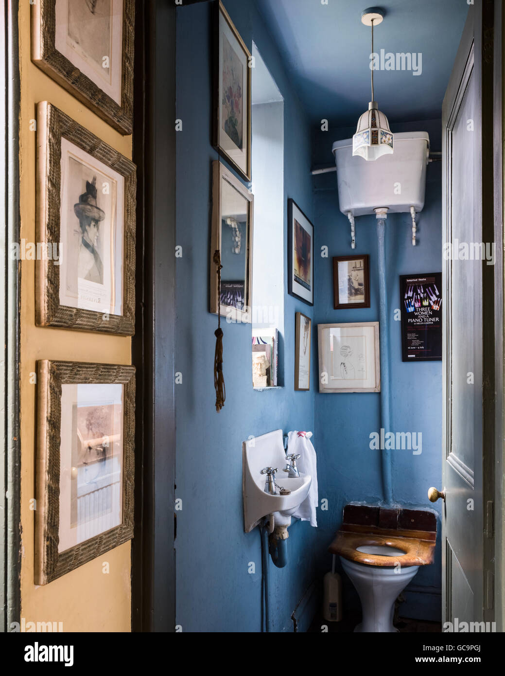 Gerahmte Kunstwerke in blauen Waschraum mit Wand-Zisterne in Nottinghill Haus, London, UK Stockfoto