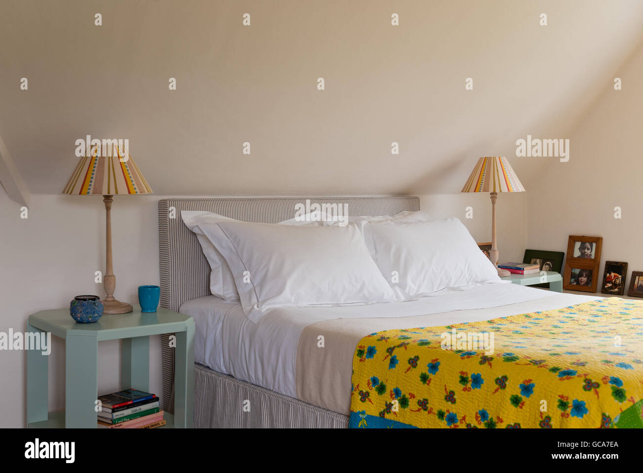 Helles gelb gemusterten indische Quilt in Ferienhaus Schlafzimmer mit Dachschrägen. Stockfoto
