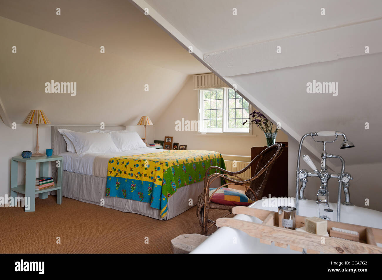 Helles gelb gemusterten indische Quilt in Ferienhaus Schlafzimmer mit Dachschrägen. Das Bad ist ein Clyde von Drummonds Stockfoto