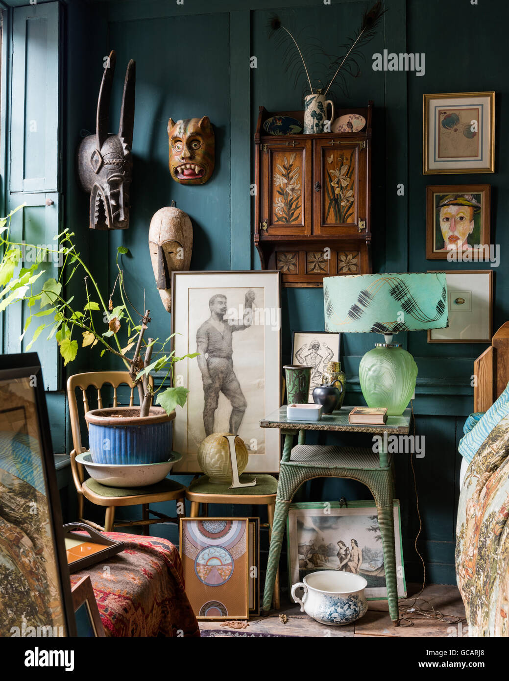 Skurrile Teal farbigen Holz getäfelten Zimmer gefüllt mit verschiedenen Objekten - afrikanische Masken, verschiedene Kunstwerke und englische Keramik Stockfoto