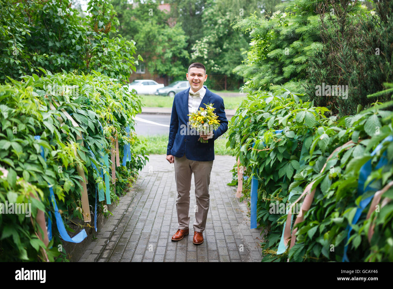 Glückliche Bräutigam hält einen Hochzeitsstrauß, Sommerzeit Stockfoto