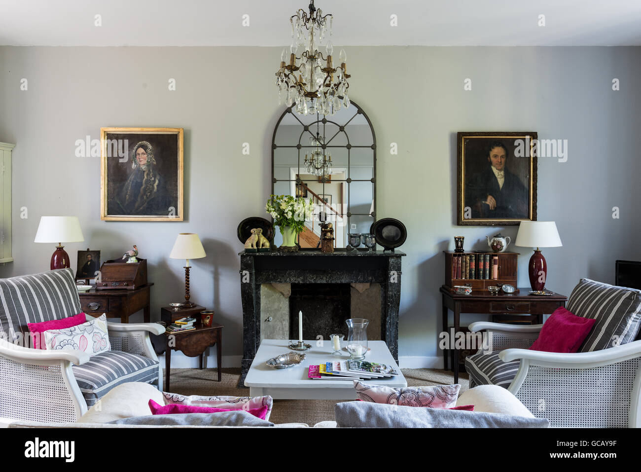 Licht grau Wohnzimmer mit Kristall-Kronleuchter, Öl gemalten Porträts und gestreiften Polstersessel Stockfoto