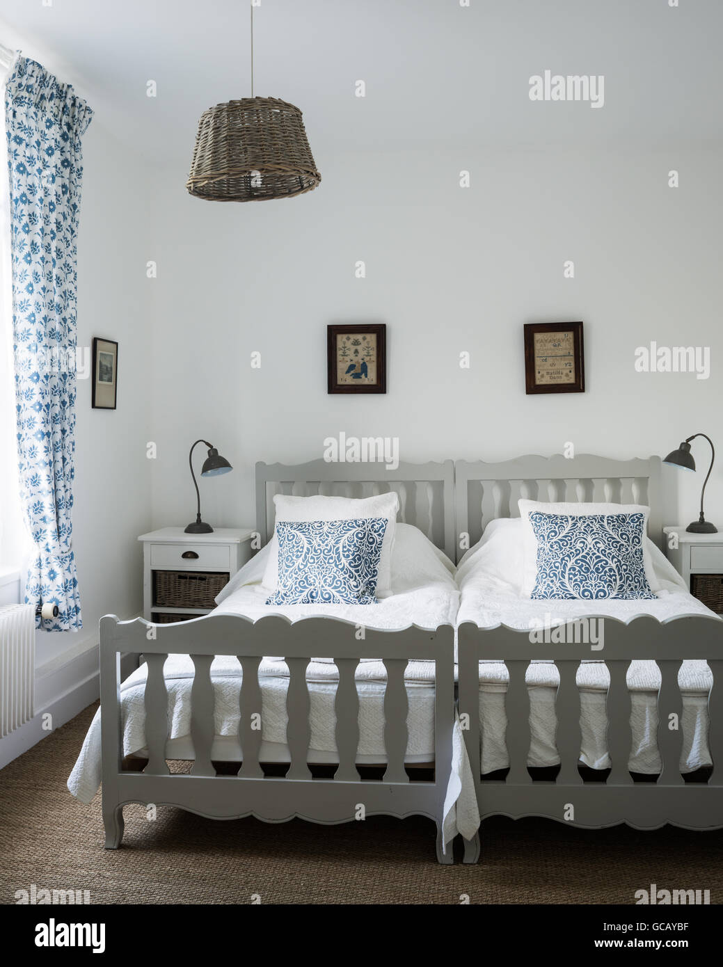 Zwei Einzelbetten im Zimmer mit schwedischen Block drucken, Vorhänge und Korb Lampenschirm Stockfoto