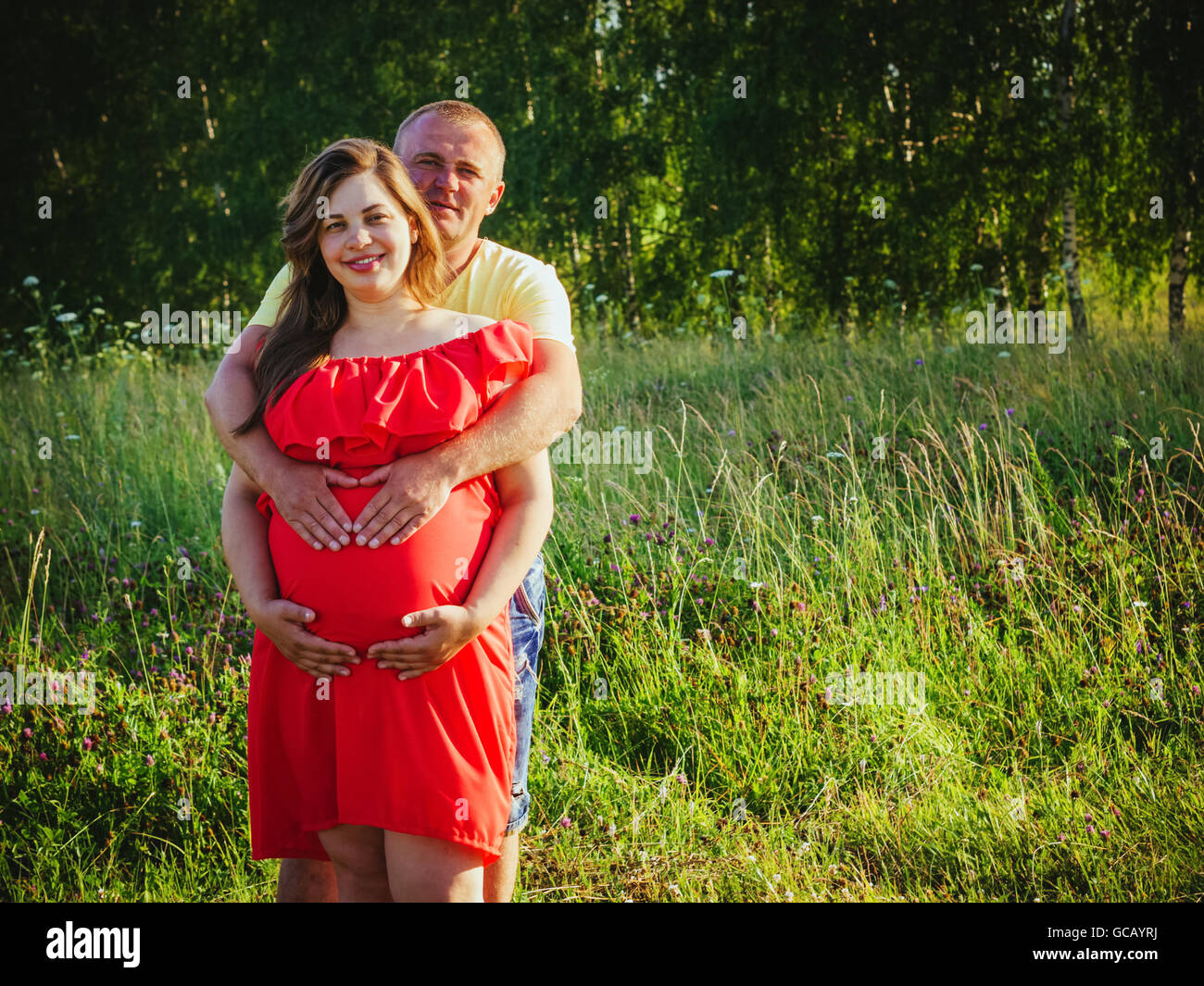 Schwangere Frau und ihr Mann mit den Händen auf Bauch im freien Stockfoto