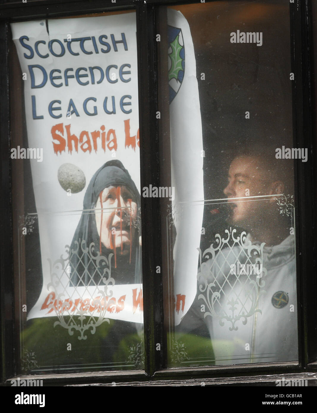 Ein Mann stellt ein SDL-Poster in das Fenster von Jenny Has Bar auf der Royal Mile in Edinburgh. Antifaschistische Demonstranten zielten auf eine Versammlung der rechtsextremen Scottish Defence League (SDL) ab. Demonstranten sagten, Mitglieder der SDL seien in Jenny Has Bar und schwor, in der Gegend zu bleiben, bis sie die Stadt verließen. Stockfoto