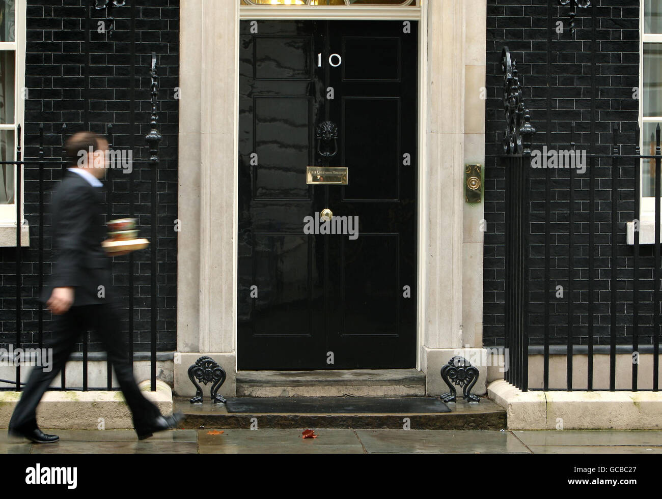 Ein Mann außerhalb der Downing Street 10 in London, wie der konservative Führer David Cameron und sein liberal-demokratischer Amtskollege Nick Clegg heute in der Downing Street 10 aufgefordert haben, sich mit den Vorwürfen der Mobbing von Mitarbeitern zu befassen. Stockfoto