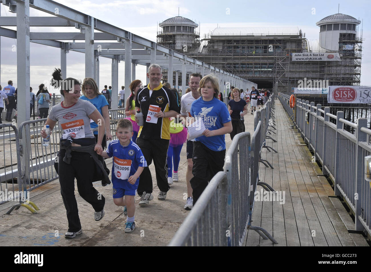 Charity-Läufer laufen am Grand Pier von Weston-super-Mare entlang, während sie am in Sainsbury's Sport Relief Mile Charity Fun-Run teilnehmen. Stockfoto