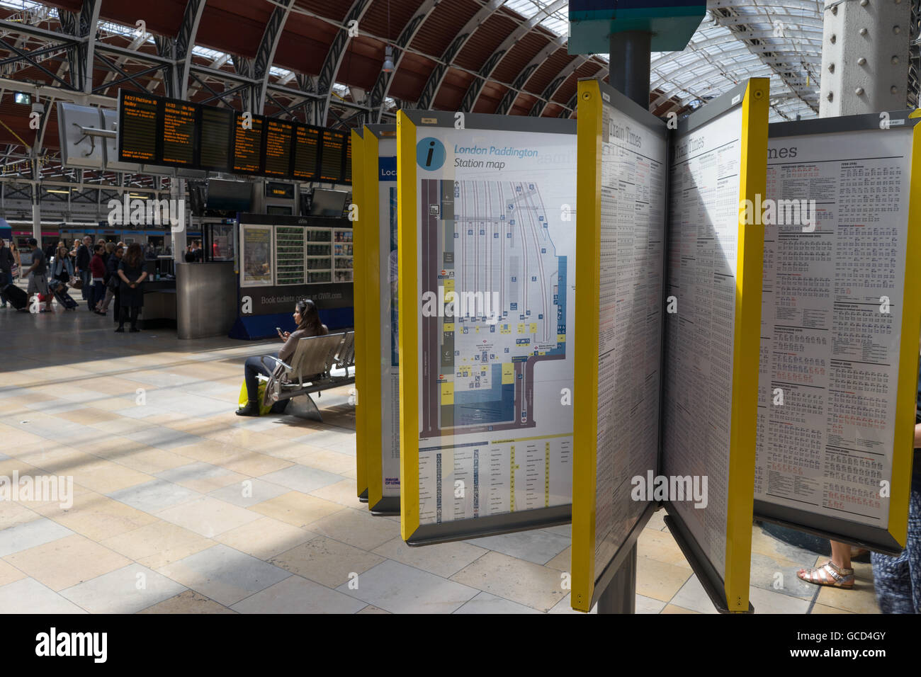 Bahn-Fahrpläne und Informationstafeln mit Passagier wartet Stockfoto