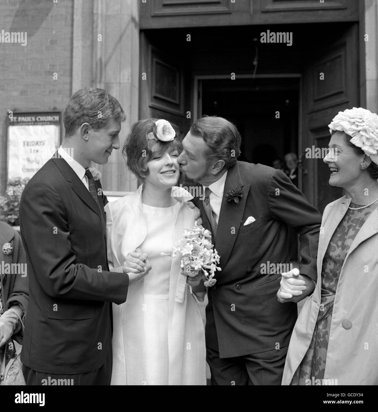 Der Schauspieler Sir Michael Redgrave küsst seine neue Schwiegertochter, die 23-jährige Deidre Hamilton-Hill, nach ihrer Heirat mit Sir Michaels Schauspielersohn Corin Redgrave, Left, in der St. Paul's Church, Covent Garden, London. Stockfoto