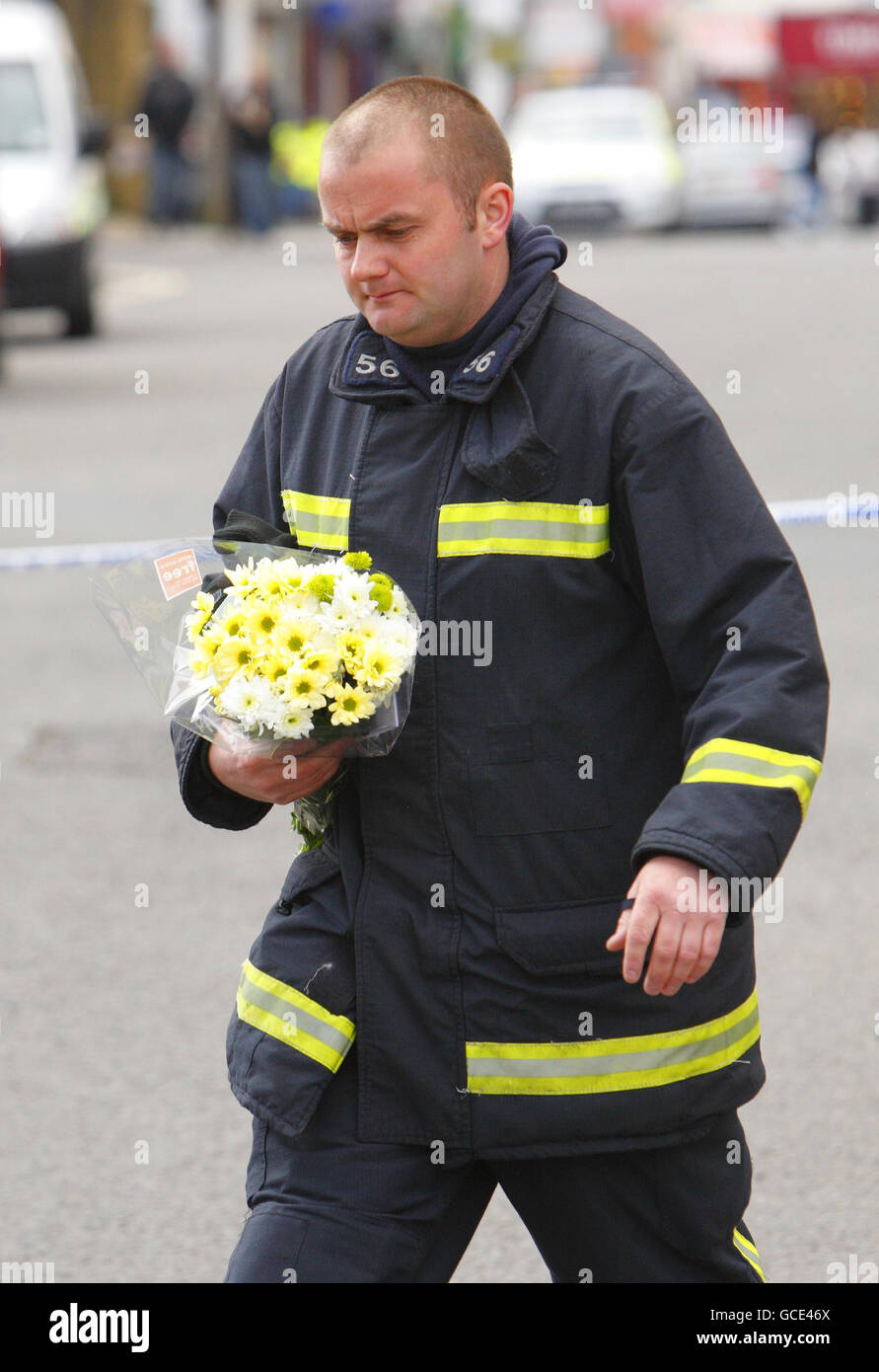 Ein Feuerwehrmann legt Blumen am Fuße der Shirley Towers in Southampton, nachdem die Feuerwehrleute Alan Bannon und James Shears über Nacht bei einem Brand auf dem Wohnblock im Stadtteil Shirley getötet wurden. Stockfoto