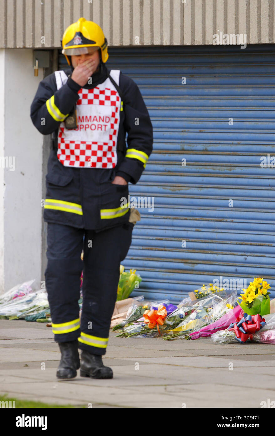 Ein Feuerwehrmann geht an Blumen am Fuße der Shirley Towers in Southampton vorbei, nachdem die Feuerwehrleute Alan Bannon und James Shears bei einem Brand auf dem Wohnblock im Stadtteil Shirley über Nacht getötet wurden. Stockfoto