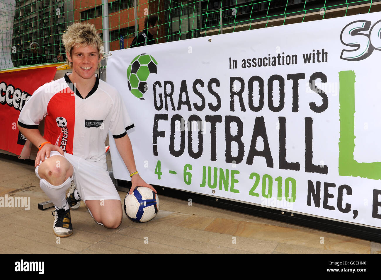 Fußball Freestyle Weltmeister John Farnworth posiert neben einem Plakat für die Veranstaltung während der Grass Roots Football Live Einführungsveranstaltung Stockfoto