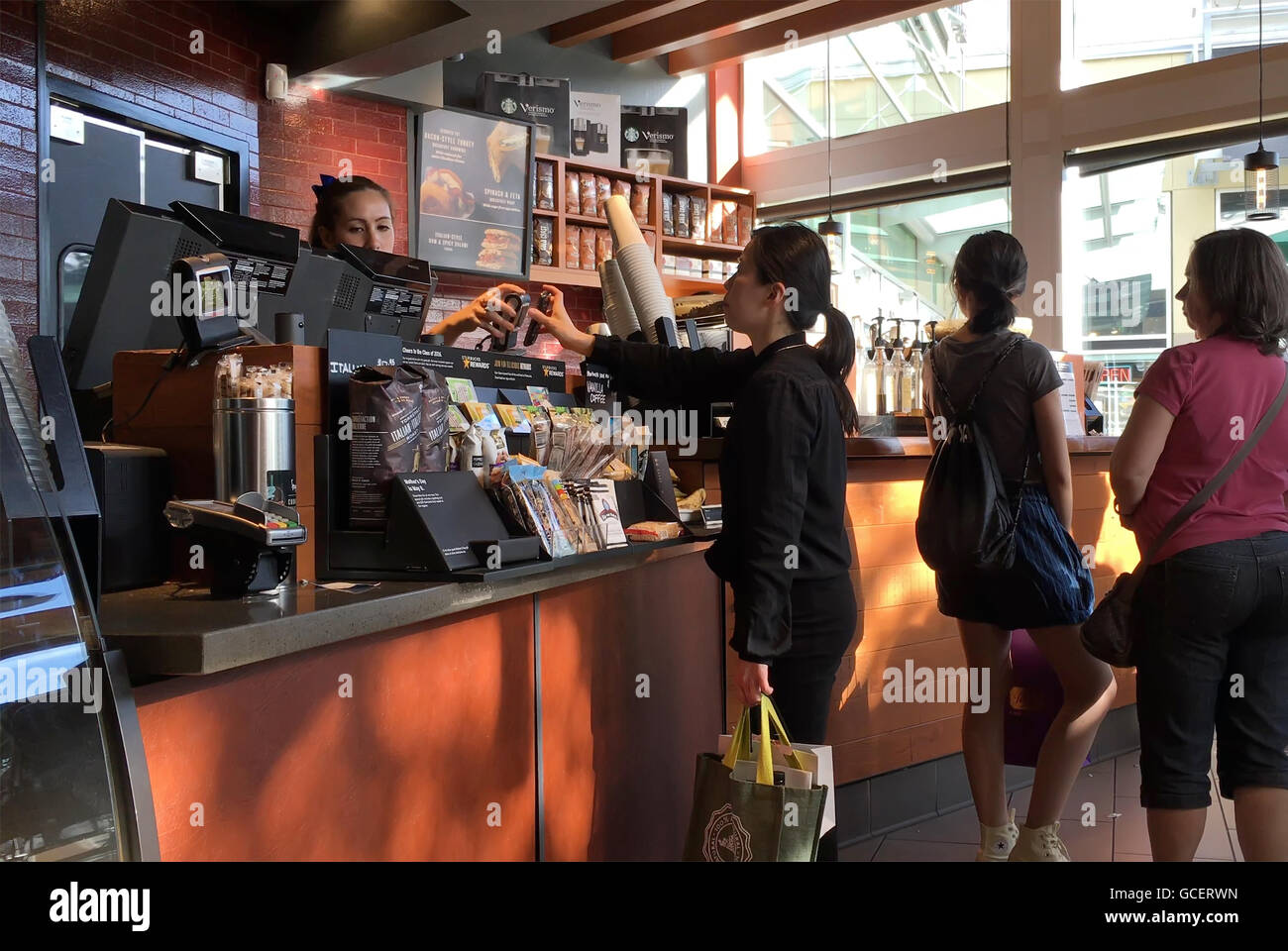Frau mit Apple Pay zu bezahlen ihren Kaffee im Starbucks Coffee shop Stockfoto