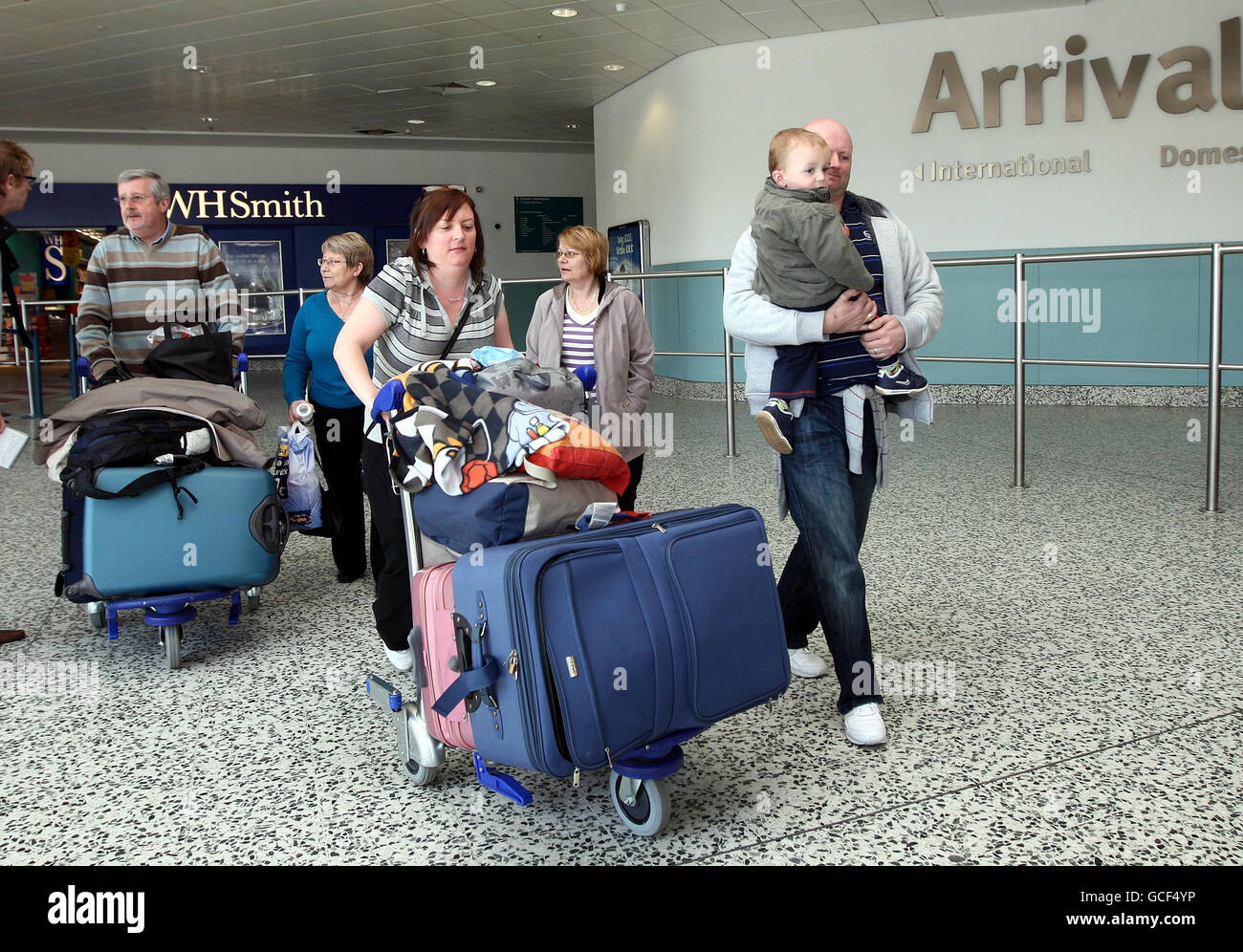 Lisa und Nick Macardy mit ihrem Sohn Joshua aus Manchester mit Tante Marilyn Shuck (blaue Spitze) und Pauline Shuck (Mutter) kommen heute Morgen am Flughafen Birmingham an und kehren nach fünf Tagen Wartezeit aus München zurück. Heute hat sich der britische Luftraum inmitten eines fortwährenden Streit über Flugbeschränkungen, die durch die Vulkanaschewolke verursacht wurden, wieder geöffnet. Stockfoto