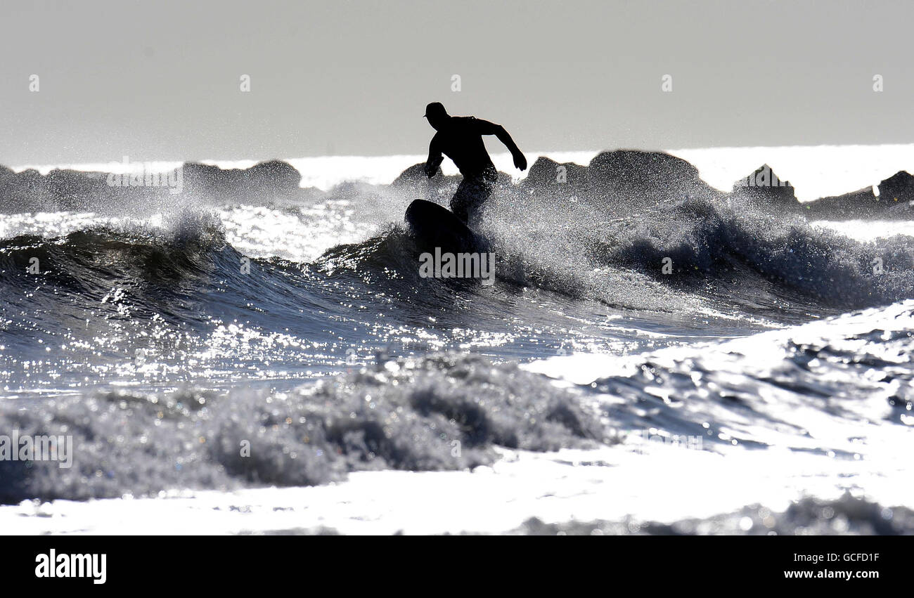 Ein Surfer, der das Frühlingswetter vor Tynemouth Beach, Tyne und Wear genießt. Stockfoto