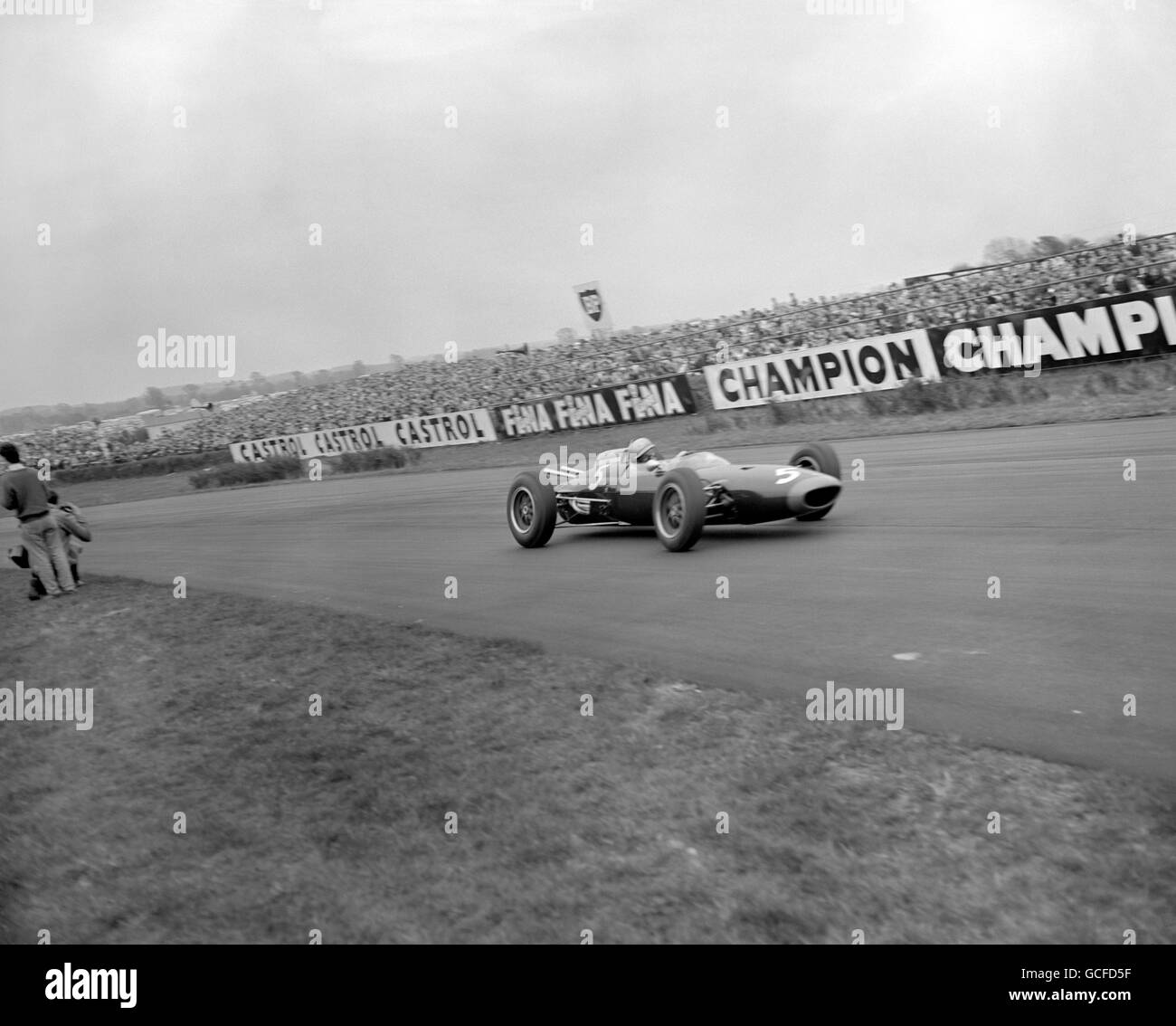John Surtees fährt mit einem Lola Climax und nimmt Madgwick Corner ein und surft die Goodwood '100' für Glover Trophy. Stockfoto