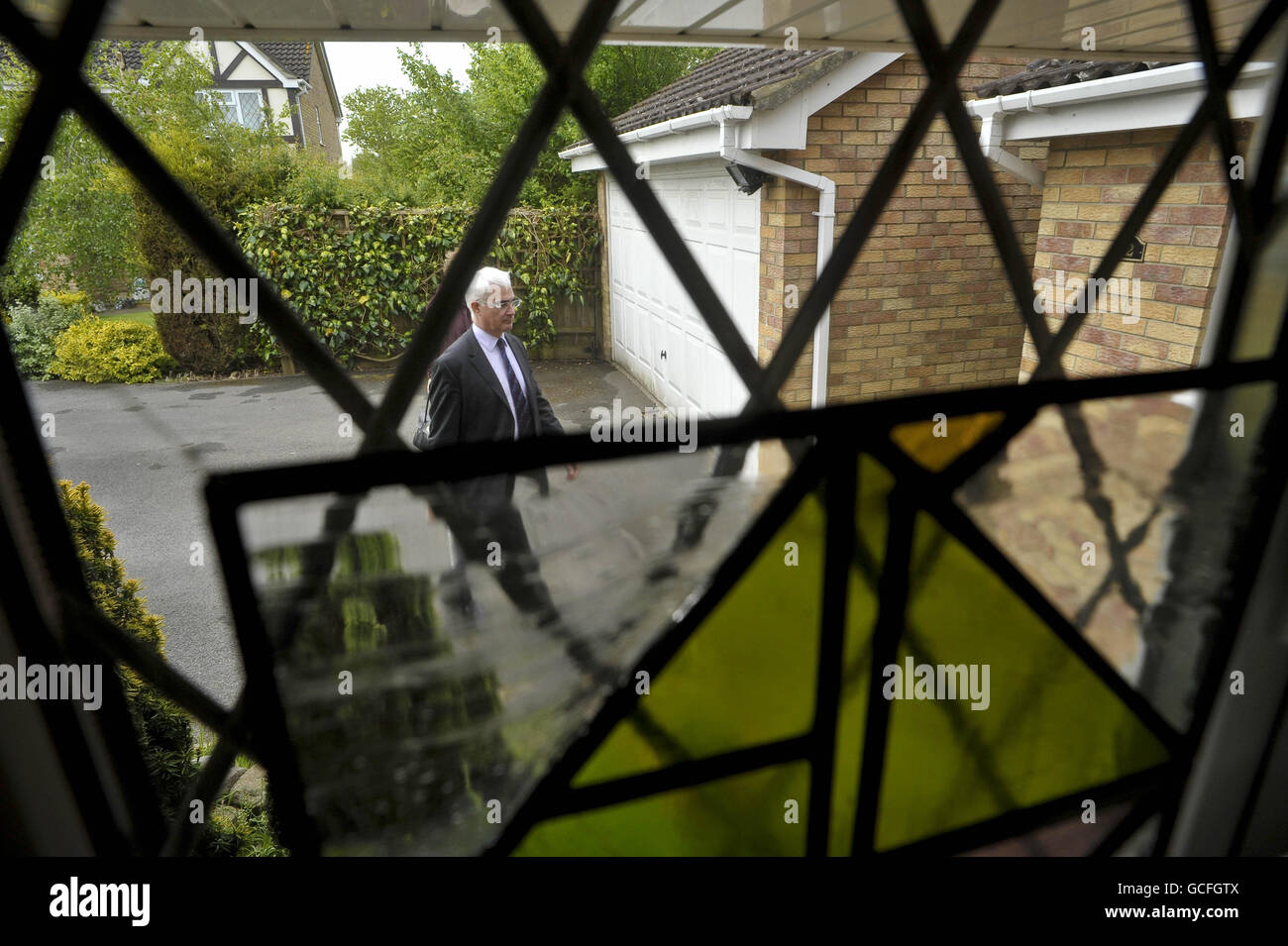 Kanzler Alistair Darling wird durch ein Bleiglasfenster abgebildet, als er im Haus eines Labour-Unterstützers ankommt, um Fragen zu diskutieren, mit denen die Wähler bei den bevorstehenden Parlamentswahlen in Kingswood, Bristol, konfrontiert sind. Stockfoto
