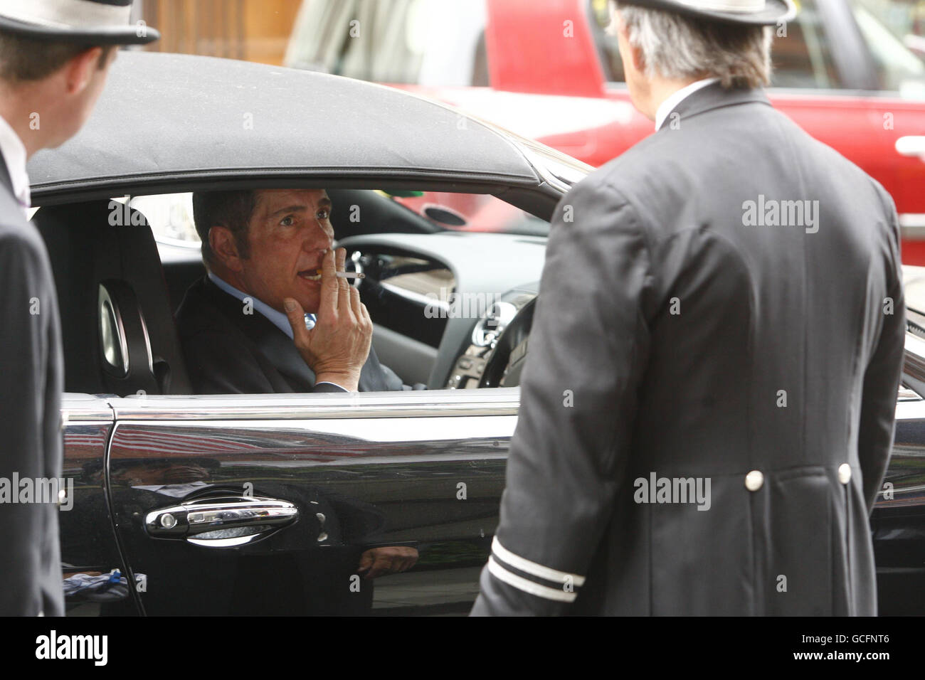 Der Fernsehmoderator Dale Winton holt Claridges Portiers beim Rauchen einer Zigarette Hilfe ein, als er bei Claridge's im Zentrum von London zur Hochzeit von David Walliams und Lara Stone ankommt. Stockfoto