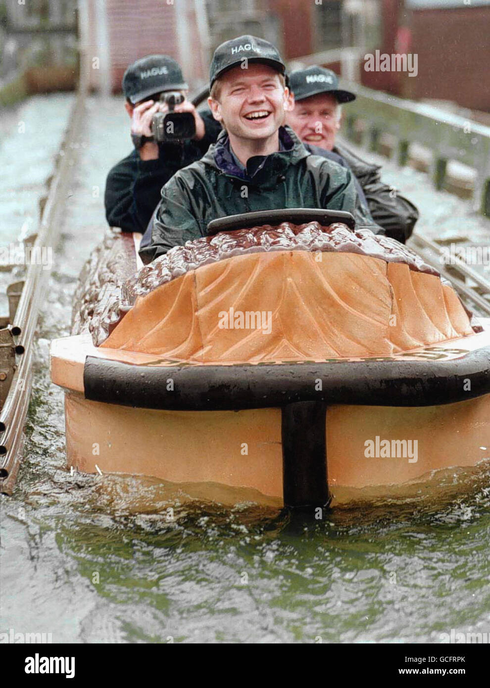 DER KONSERVATIVE PARTEICHEF WILLIAM HAGUE NAHM BUCHSTÄBLICH DEN SPRUNG IN CORNWALL AUF DER WASSERRUTSCHE IM FREIZEITPARK FLAMBARDS IN DER NÄHE VON HELSTON AUF DER EIDECHSE, BEGLEITET VON DEM STELLVERTRETENDEN STABSCHEF SEB COE UND DEM SPRECHER VON CORNWALL, DAVID HARRIS, WÄHREND EINER TOURNEE DURCH GROSSBRITANNIEN. Stockfoto