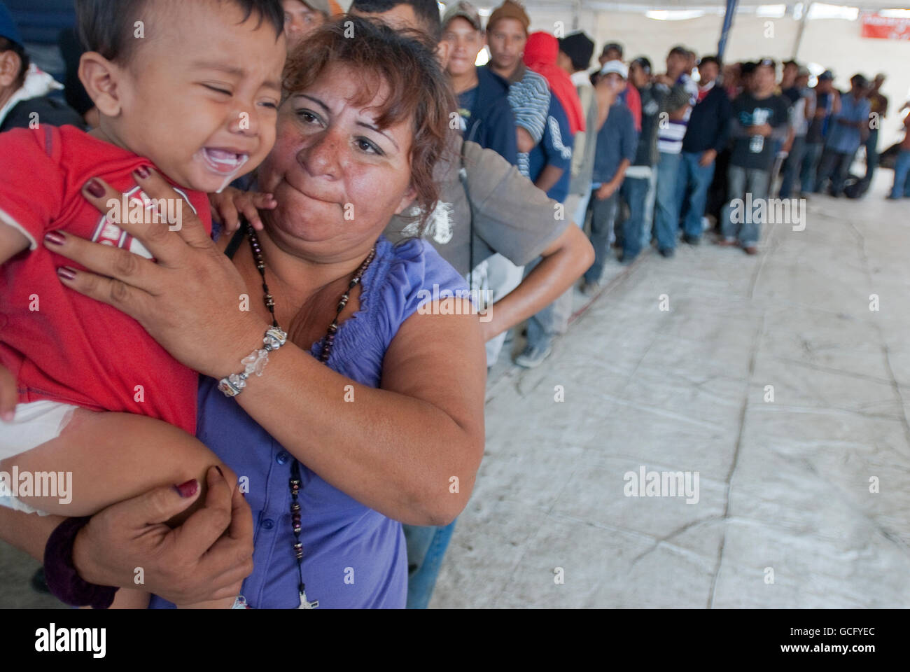 Eine Frau hält und tröstet ihren Enkel im stehen in der Schlange zum Frühstück in einem Migranten Tierheim nördlich von Mexiko-Stadt Stockfoto