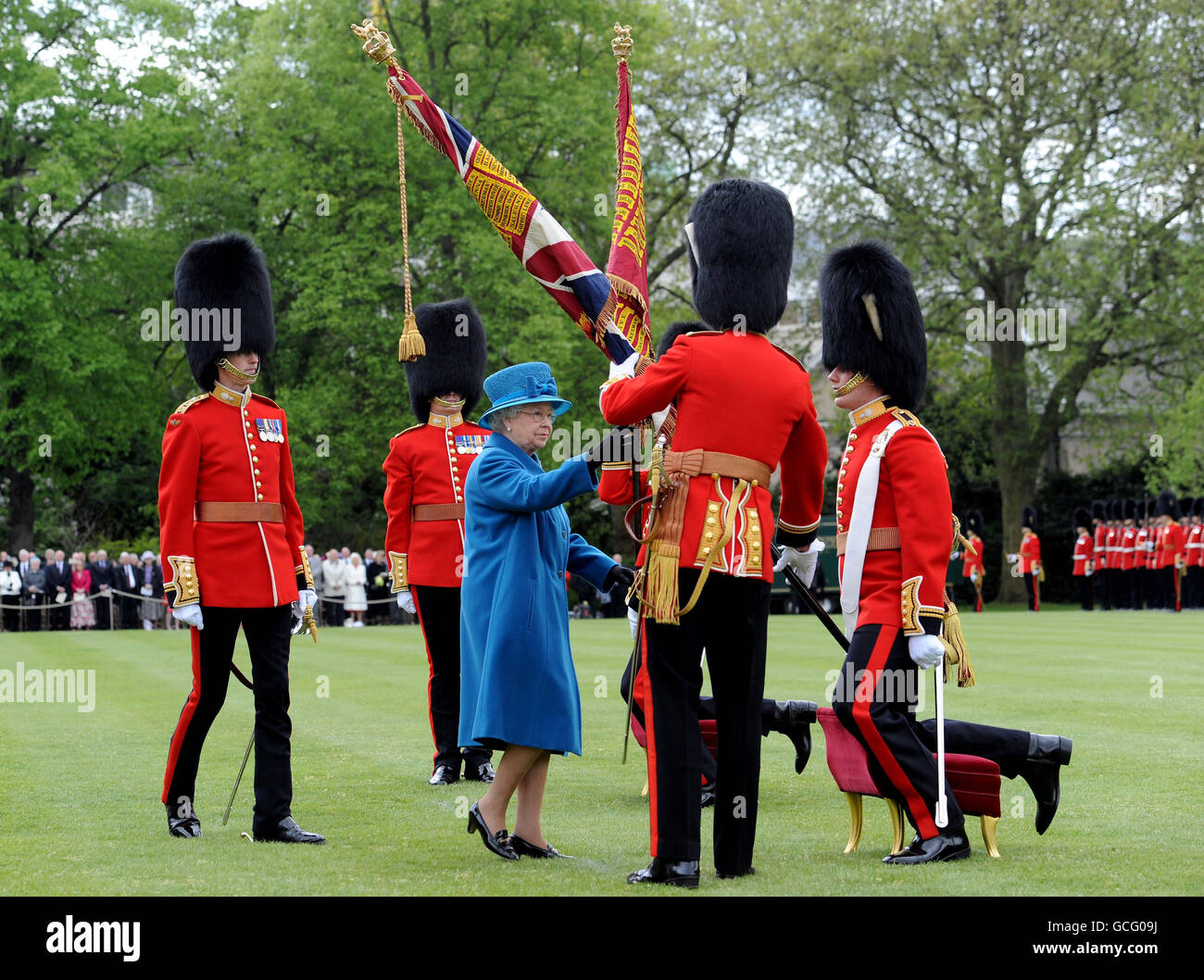 Königin Elizabeth II. Berührt die neuen Farben der Grenadier Guards, nachdem sie sie im Garten des Buckingham Palace in London präsentiert hat. Stockfoto