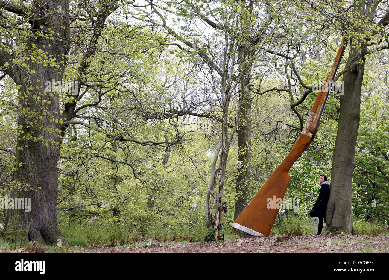 Die Künstlerin Cornelia Parker mit ihrer Arbeit "Landscape with Gun and Tree" eine 9 m hohe Stahlflinte, die an einer Buche angelehnt ist, eine der neuen Arbeiten, die heute offiziell auf Jupiter Artland in der Nähe von Edinburgh vorgestellt werden. Stockfoto