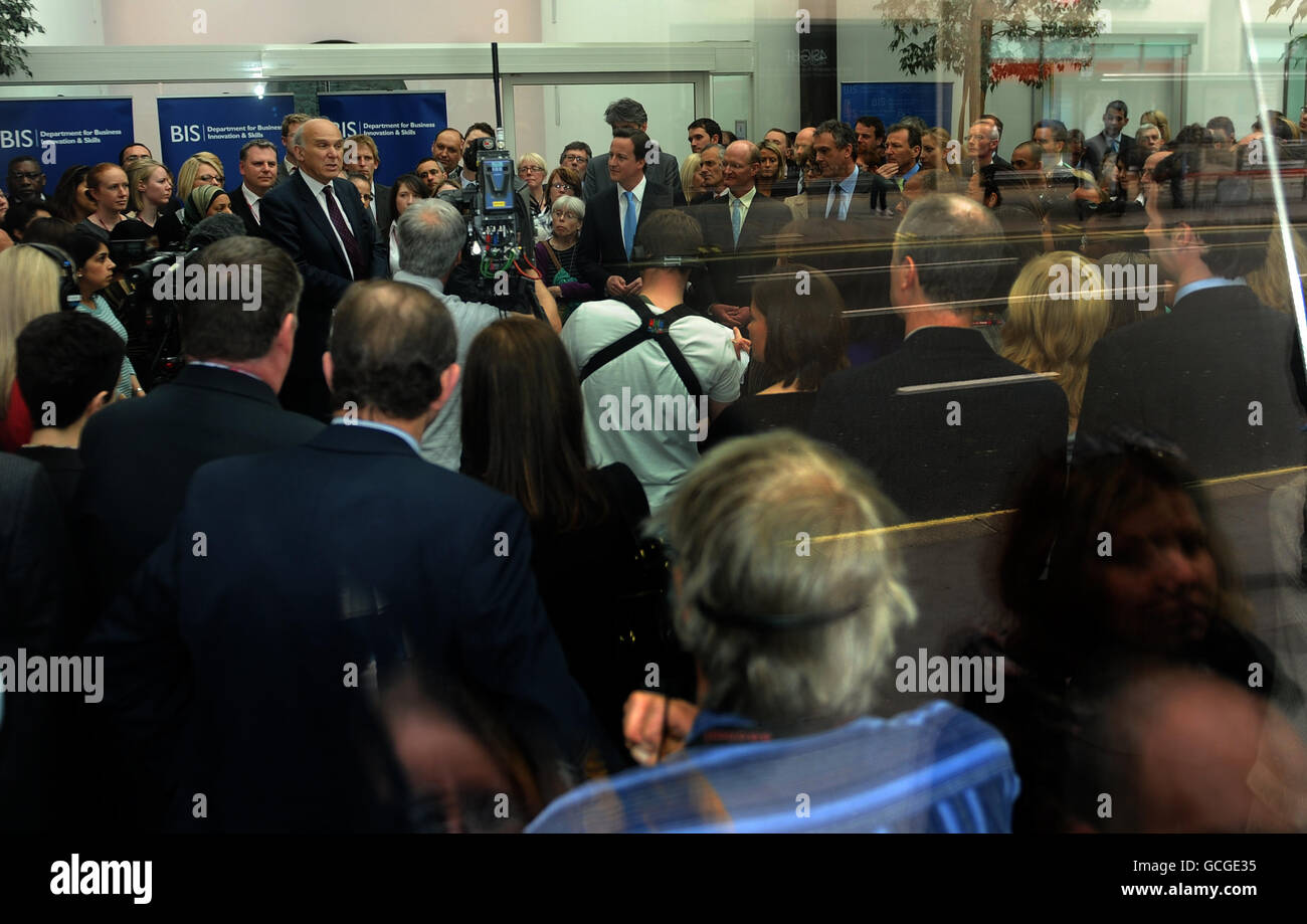 Der britische Premierminister David Cameron und David Willetts hören Vince Cable im Department of Business, Enterprise and Regulatory Reform in Westminster, London, durch ein Fenster. Stockfoto