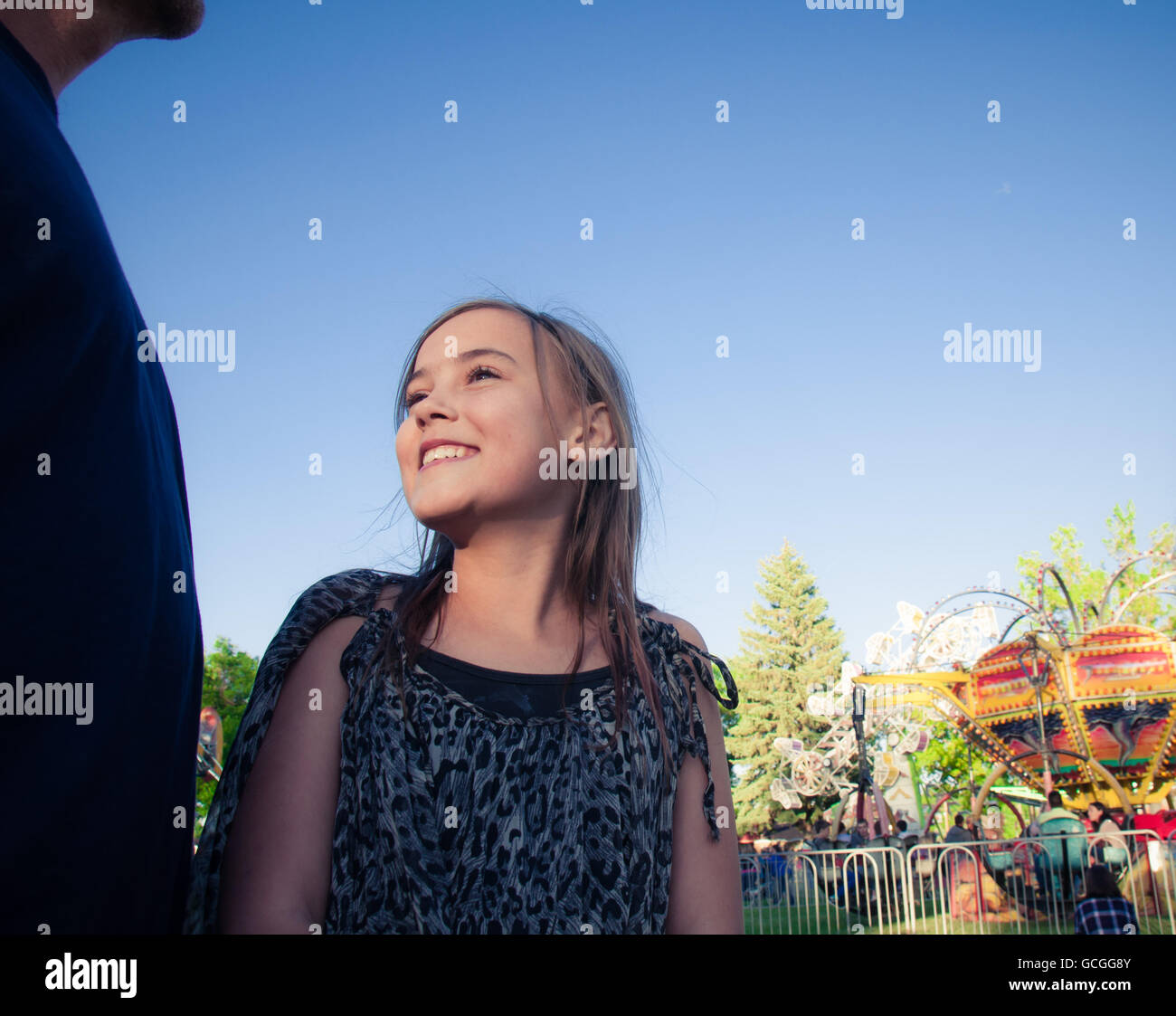 Mädchen im elementaren Alter mit ihrem Vater, der am Karneval lächelt. Stockfoto