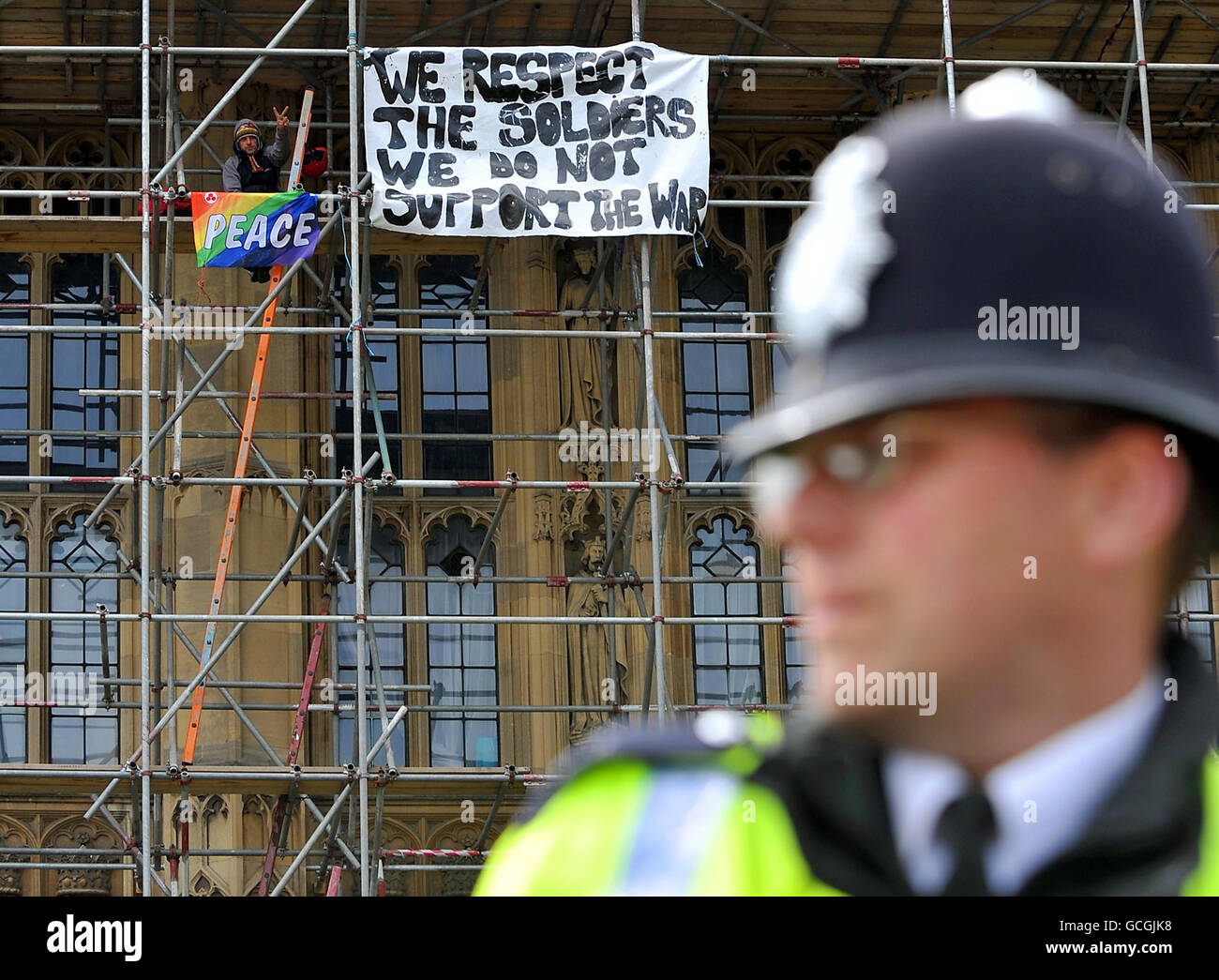 Ein Polizeibeamter sieht zu, wie ein Friedensproter während einer Demonstration gegen den Krieg in Afghanistan auf einem Gerüst im Repräsentantenhaus in Westminster, London, sitzt. Stockfoto