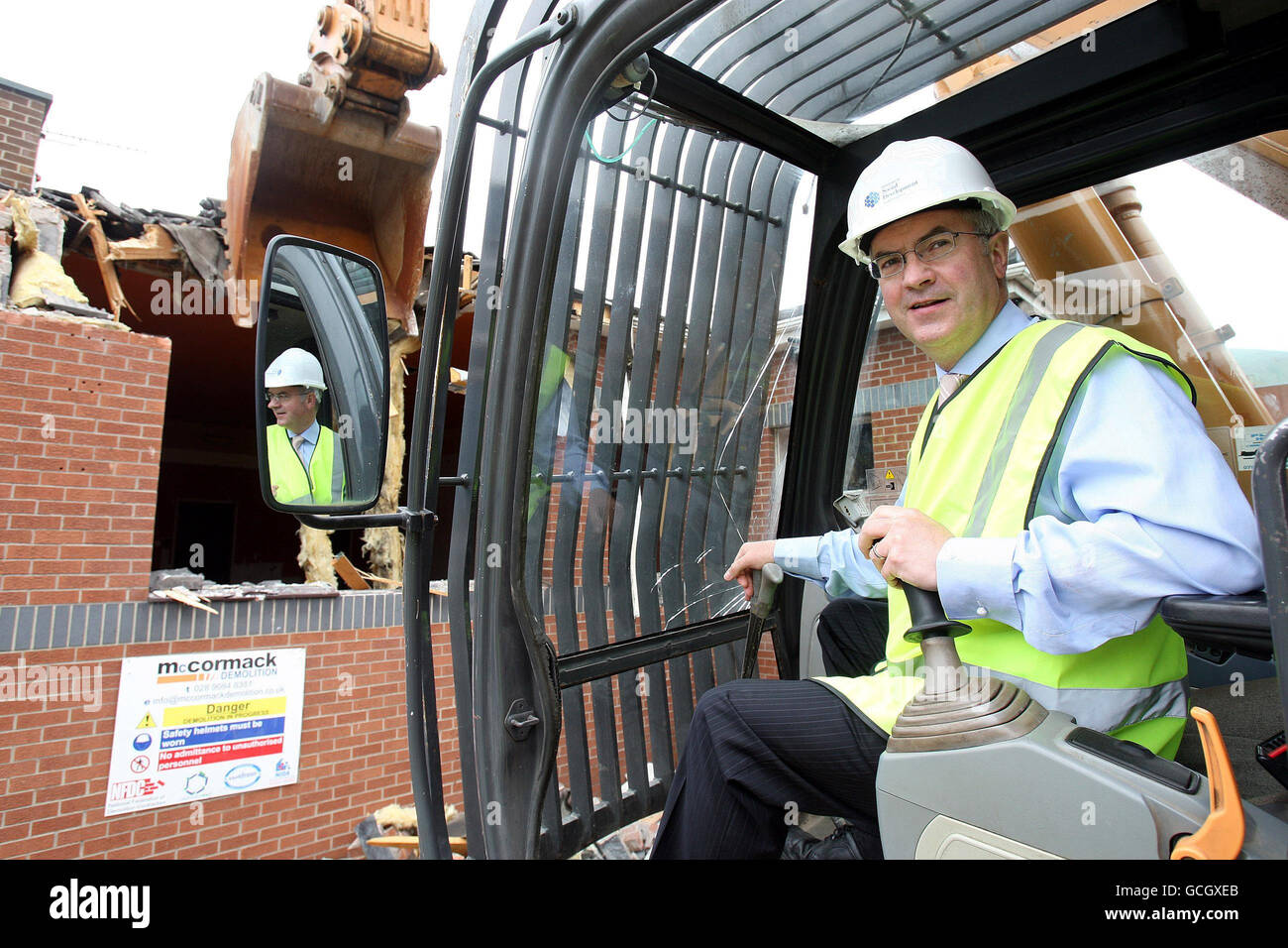 New Social Development Minster, Alex Atwood in the Driving Seat während die Abrissarbeiten am ehemaligen Standort der Bass Brewery im Westen von Belfast beginnen, soll der Standort nivelliert und durch sozialen Wohnungsbau ersetzt werden. Stockfoto