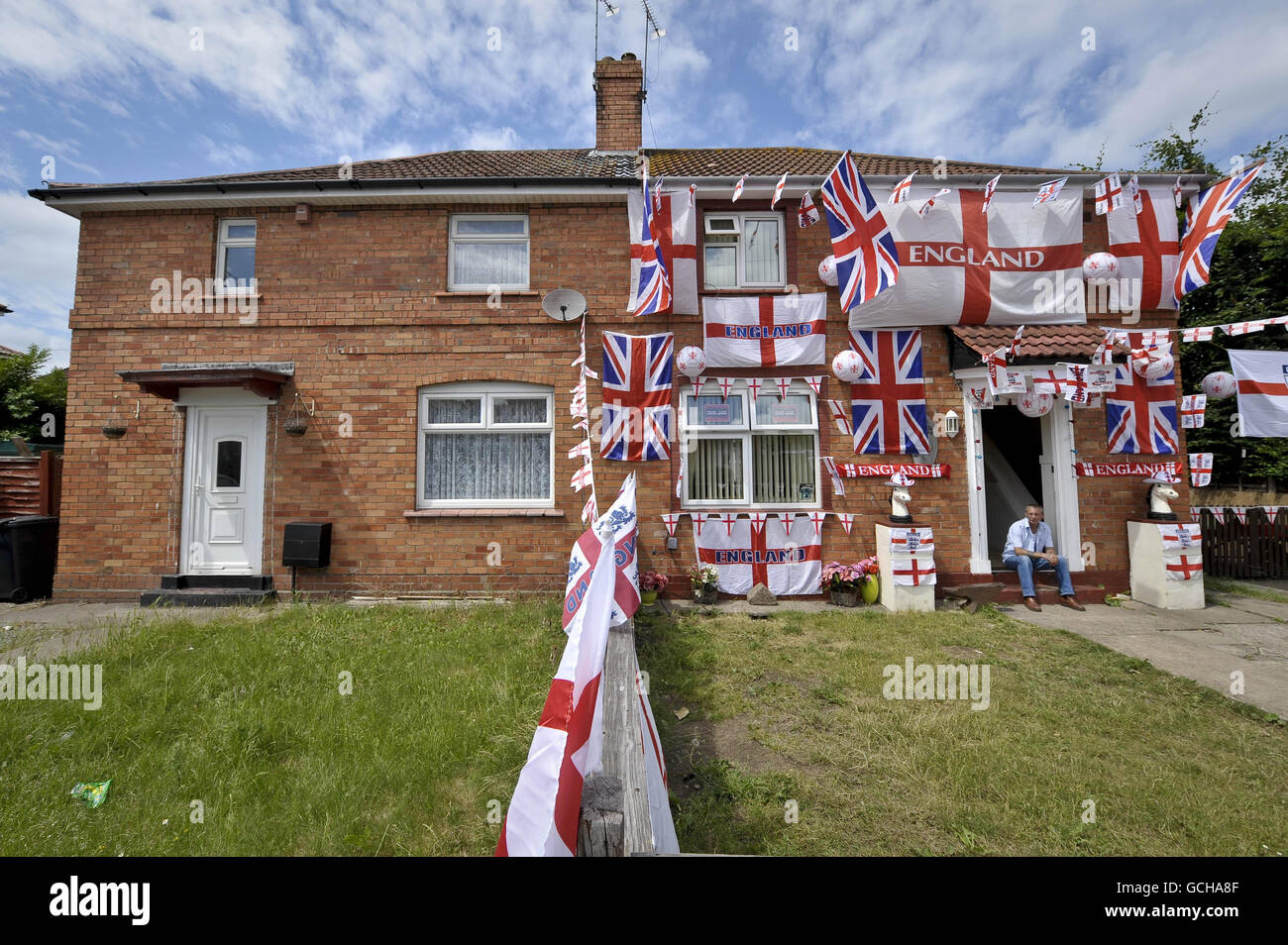 Der englische Fußballfan Paul Griffin killt vor seiner Haustür in seinem Doppelhaus im Viertel Knowle West in Bristol, das er mit englischen Flaggen geschmückt hat. Stockfoto