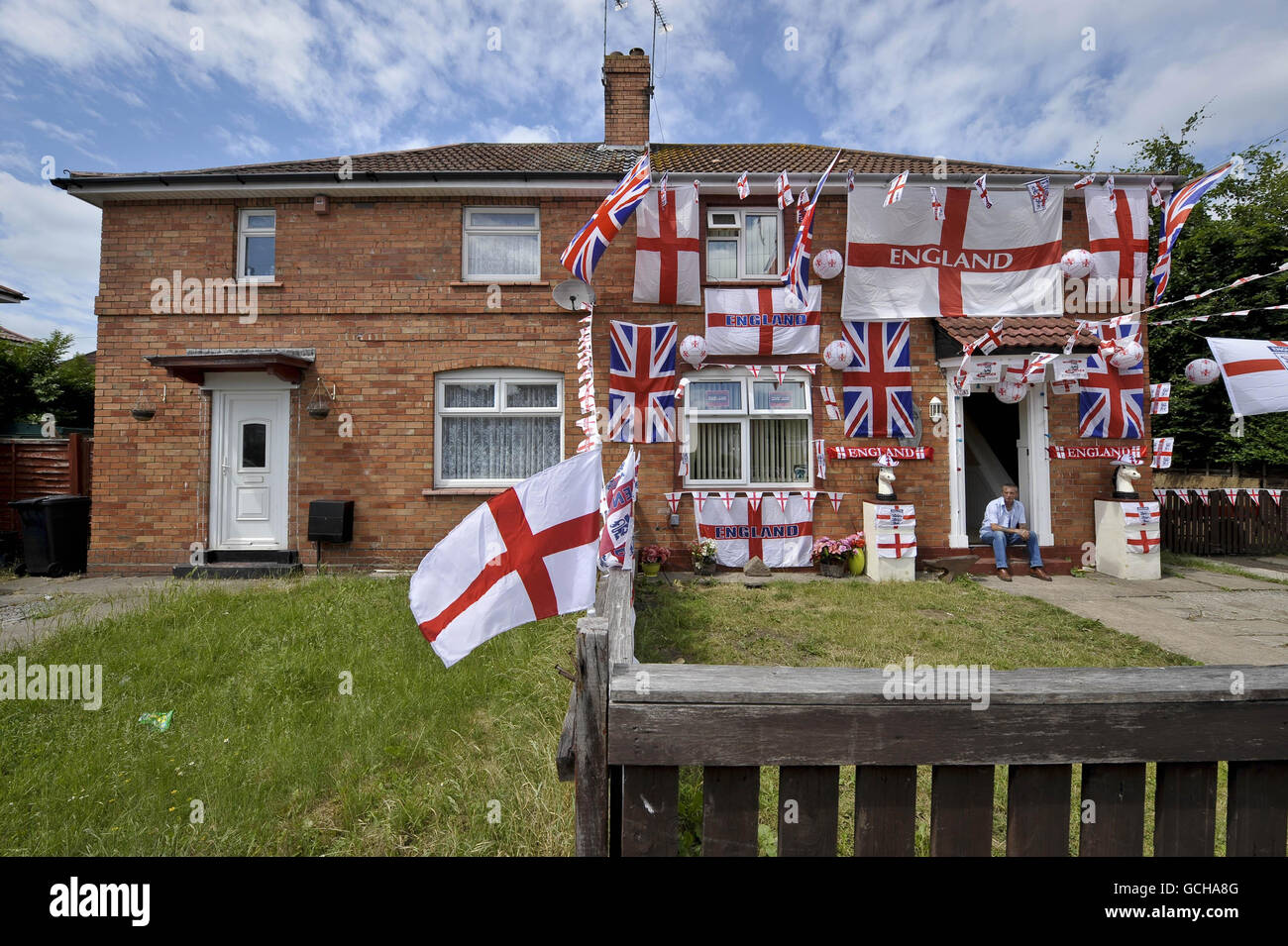 Der englische Fußballfan Paul Griffin killt vor seiner Haustür in seinem Doppelhaus im Viertel Knowle West in Bristol, das er mit englischen Flaggen geschmückt hat. Stockfoto
