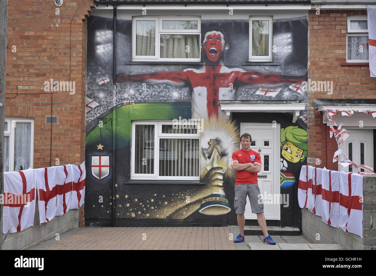 England Fußballfan Lee Bray, 34, von Knowle West, Bristol, vor seinem WM-Themenhaus, das von lokalen Graffiti-Künstlern besprüht wurde. Stockfoto