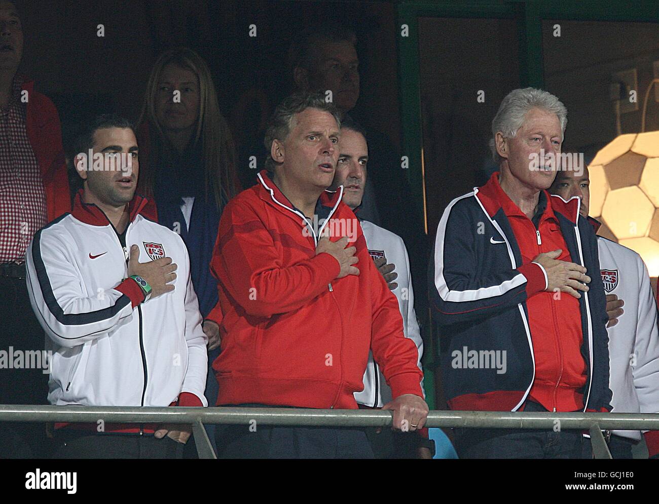Der ehemalige US-Präsident Bill Clinton (rechts) singt auf den Tribünen ihre Nationalhymne. Stockfoto