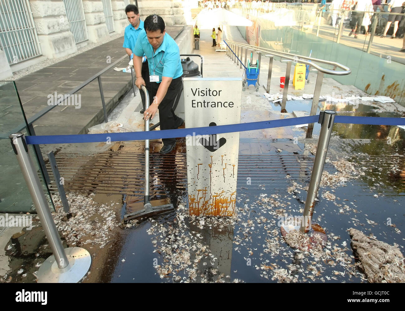 Reinigungspersonal arbeitet daran, Öl und Federn zu entfernen, die von Demonstranten vor dem Eingang zur Tate Britain in Pimlico im Zentrum von London gegossen werden, wo die Sommerparty der Tate Britain veranstaltet wird, als Teil eines Protests gegen das Sponsoring der Künste durch BP Stockfoto