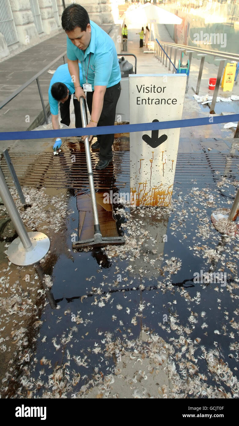 Reinigungspersonal arbeitet daran, Öl und Federn zu entfernen, die von Demonstranten vor dem Eingang zur Tate Britain in Pimlico im Zentrum von London gegossen werden, wo die Sommerparty der Tate Britain veranstaltet wird, als Teil eines Protests gegen das Sponsoring der Künste durch BP Stockfoto