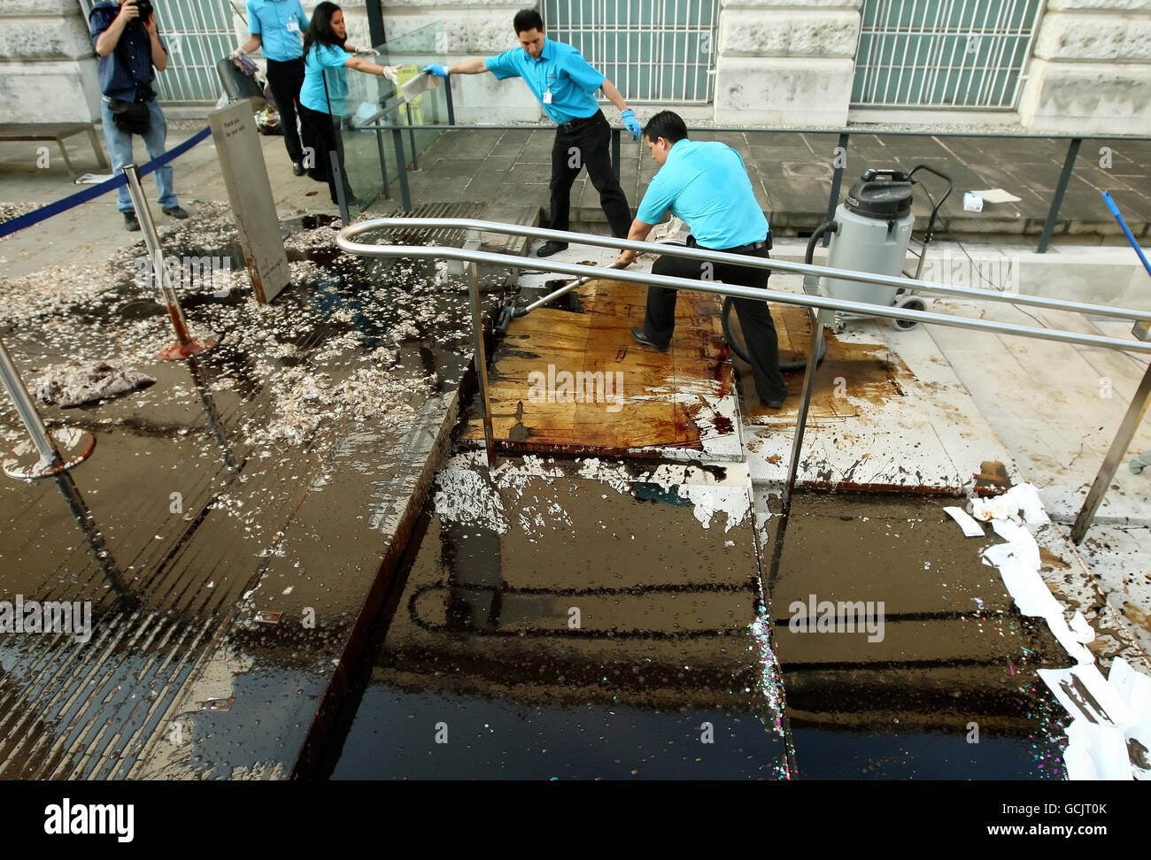 Reinigungspersonal arbeitet daran, Öl und Federn zu entfernen, die von Demonstranten vor dem Eingang zur Tate Britain in Pimlico im Zentrum von London gegossen werden, wo die Sommerparty der Tate Britain veranstaltet wird, als Teil eines Protests gegen das Sponsoring der Künste durch BP Stockfoto