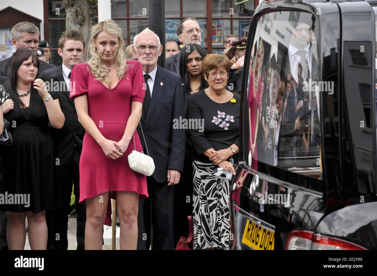 Heidi Kirkpatrick (im rosa Kleid), die Frau von Corporal Jamie Kirkpatrick, 32, vom 101 Engineer Regiment, sieht zu, wie der Sarg ihres Mannes entlang der High Street in Wootton Bassett, Wiltshire, gefahren wird. Stockfoto