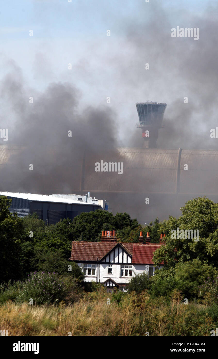 Der Rauch eines Feuers in einem Lagerhaus im Frachtbereich des Flughafens Heathrow im Westen Londons versperrt den Blick auf den Kontrollturm des Flughafens. Stockfoto