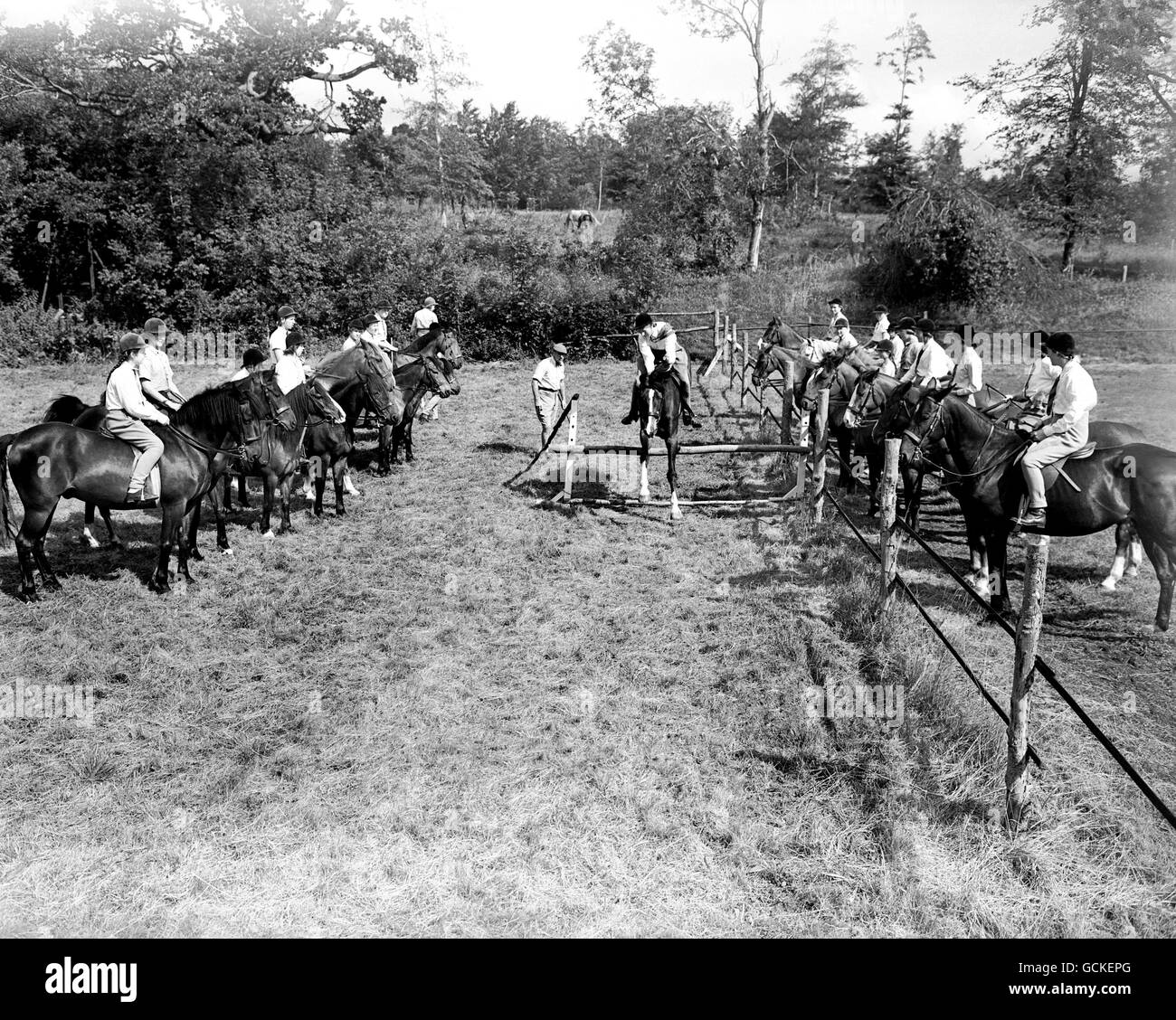 Mary Newcombe springt auf ihr Pony, beobachtet von den anderen Fahrern im Club, die abwechselnd den Zaun springen werden. Stockfoto