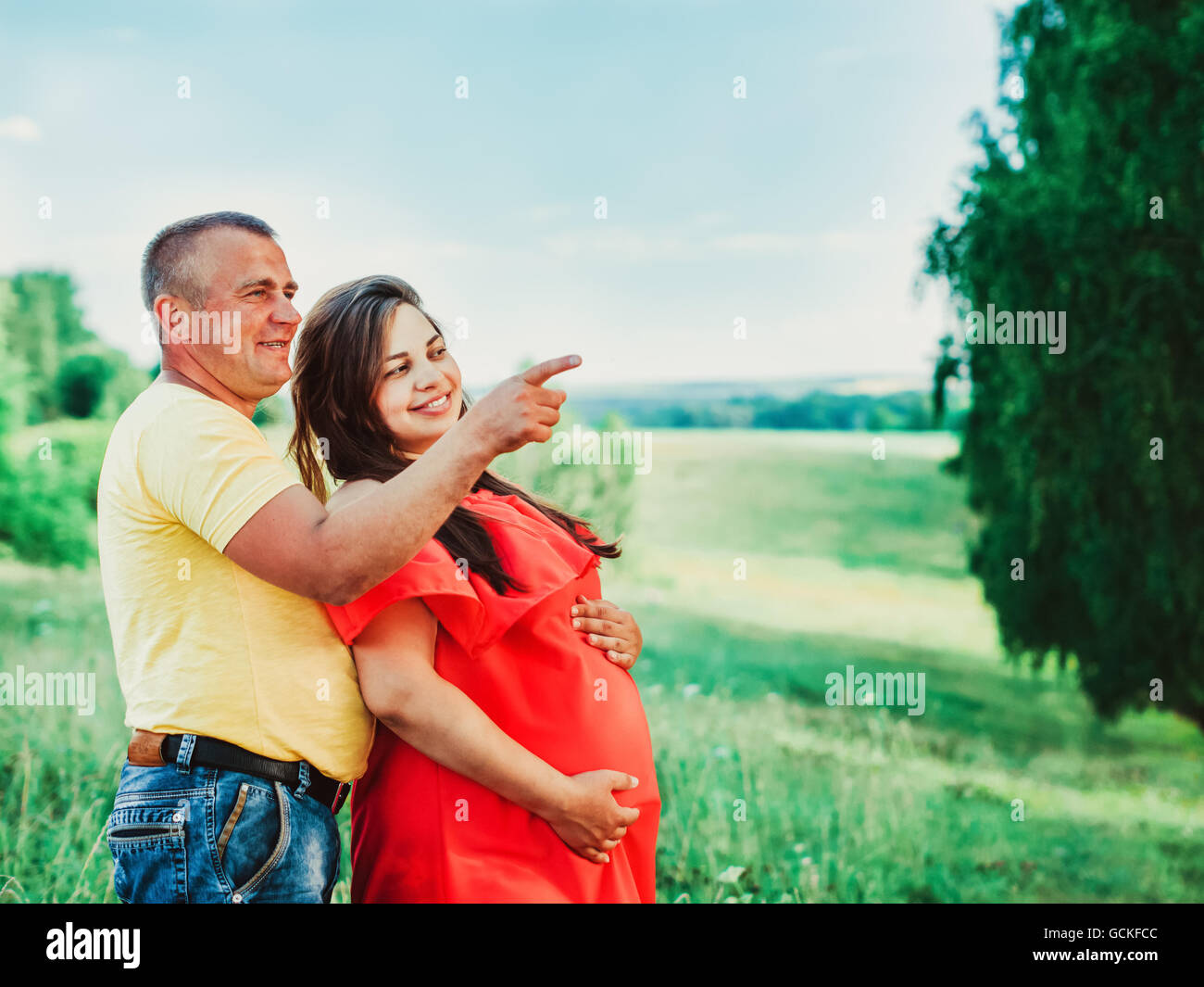 Schwangere Frau und ihr Mann mit den Händen auf Bauch im freien Stockfoto