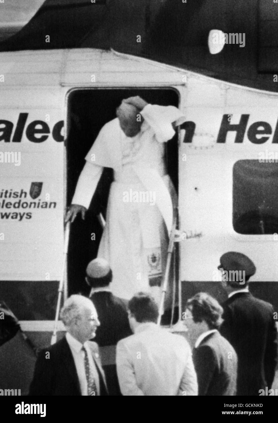 Als Papst Johannes Paul II. Bei der Ankunft am Liverpooler Flughafen Speke aus seinem Hubschrauber verschmolzen war, rauchte ihm eine steife Brise seine Schädelkappe aus dem Kopf. Stockfoto