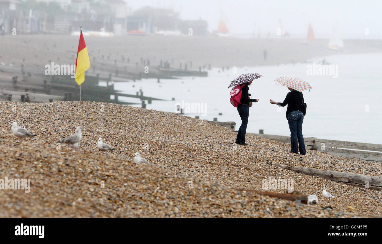 Zwei Damen machen einen Spaziergang an einem einsamen Strand in Herne Bay, Kent, während das unruhig Wetter weiter geht. Stockfoto