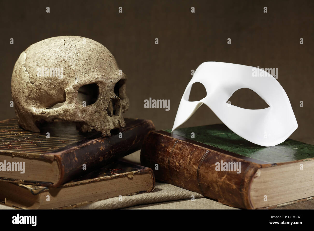 Tod-Konzept. Menschlicher Schädel auf altes Buch in der Nähe von weiße Maske Stockfoto