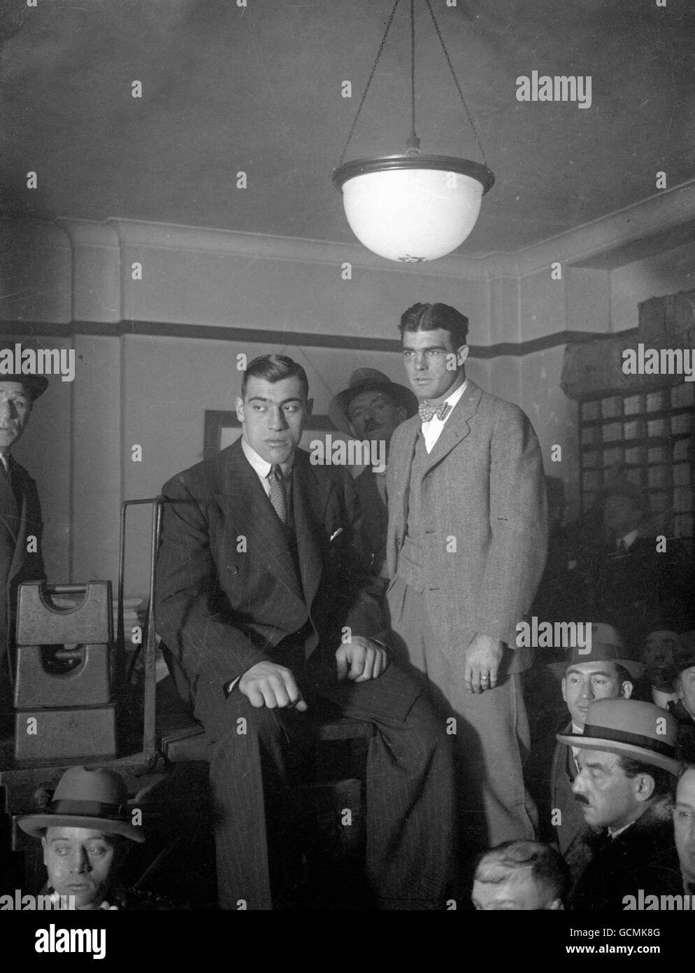 Der italienische Boxer Primo Carnera (sitzende Mitte), der heute als „die Ambling Alp“ bekannt ist, wiegt sich mit seinem Gegner, dem American Young Stribling, ein. Ihr schwerer Kampf soll morgen in der Royal Albert Hall stattfinden. Stockfoto